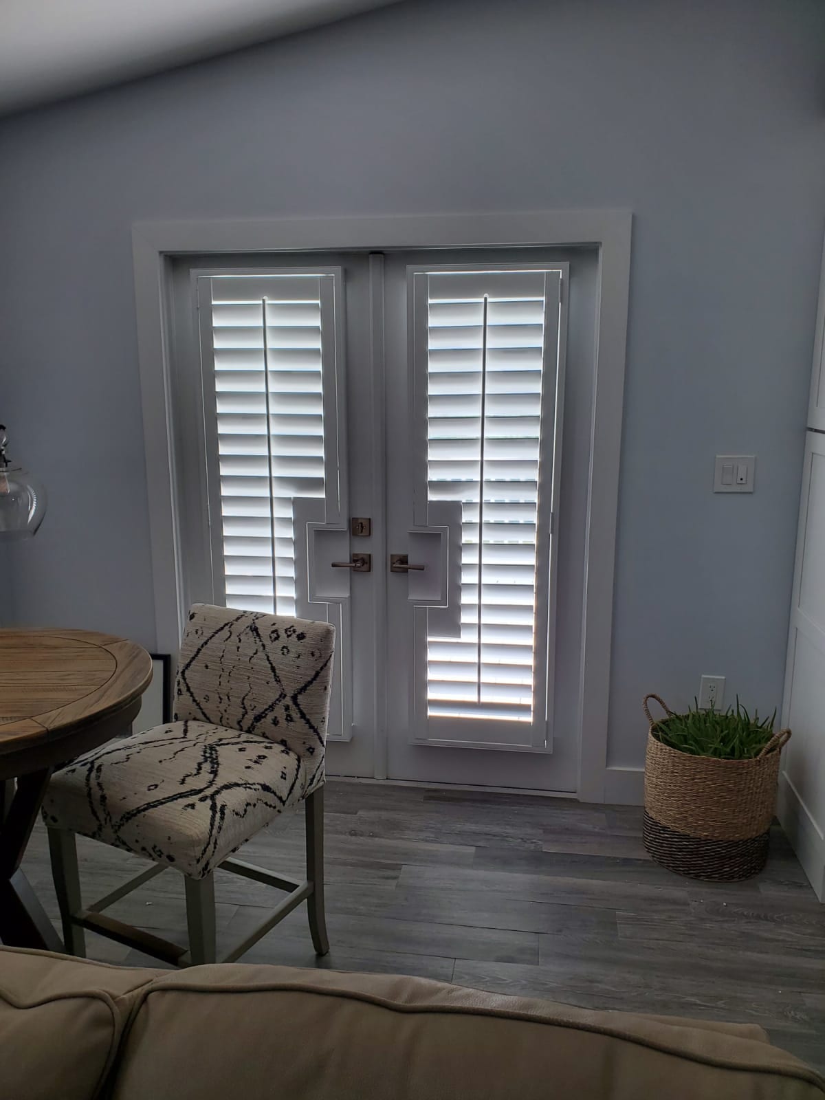 White shutters on a pair of glazed doors beside an upholstered chair