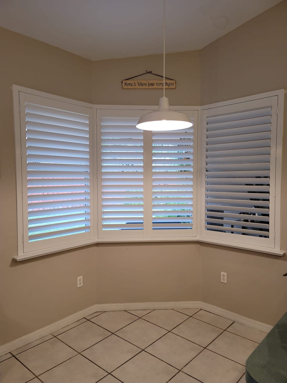 White shutters following a bay window above a tiled floor