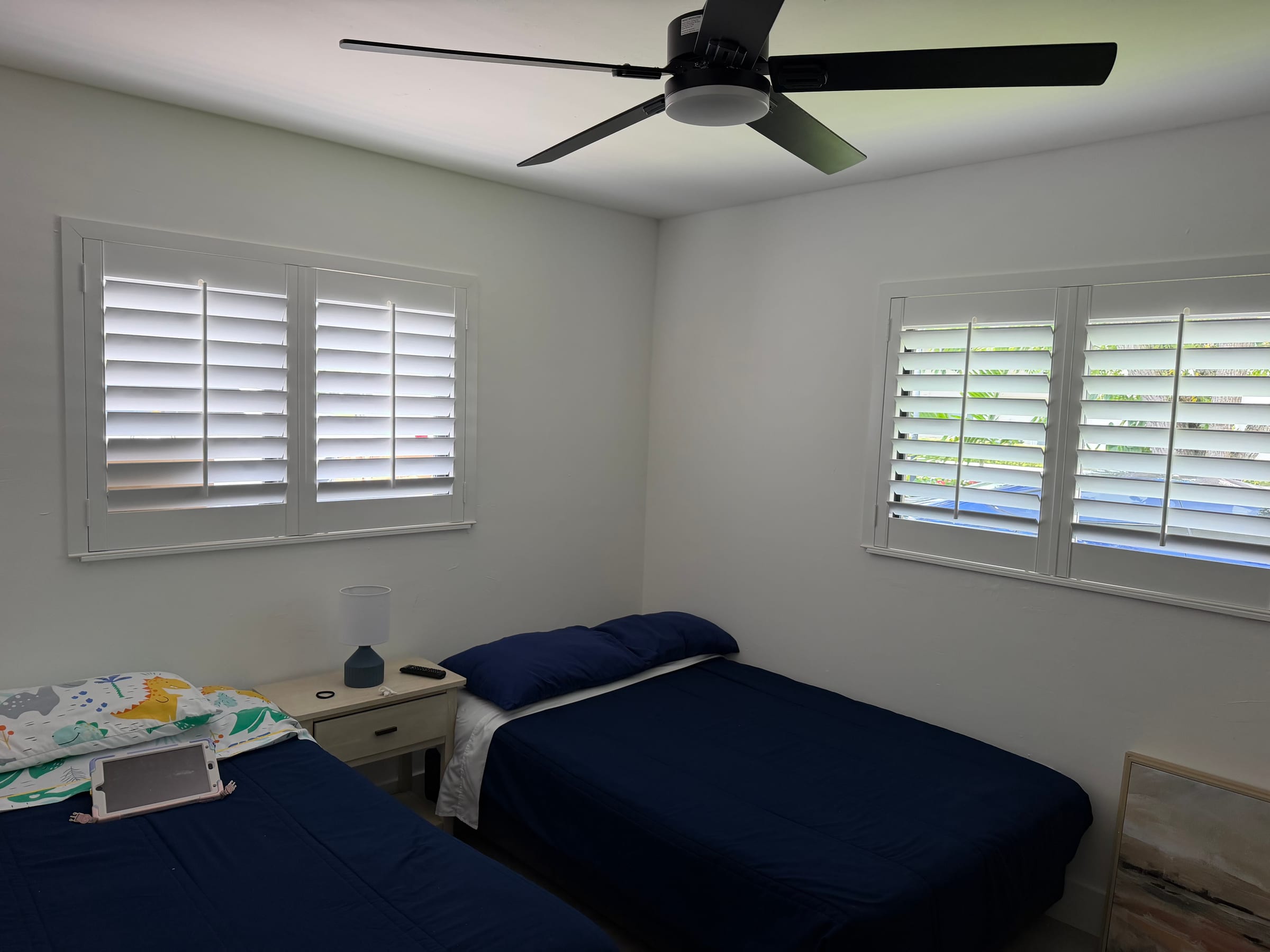 White shutters on two bedroom windows, one wide and one narrow